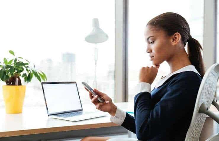 Woman sitting at desk looking at phone