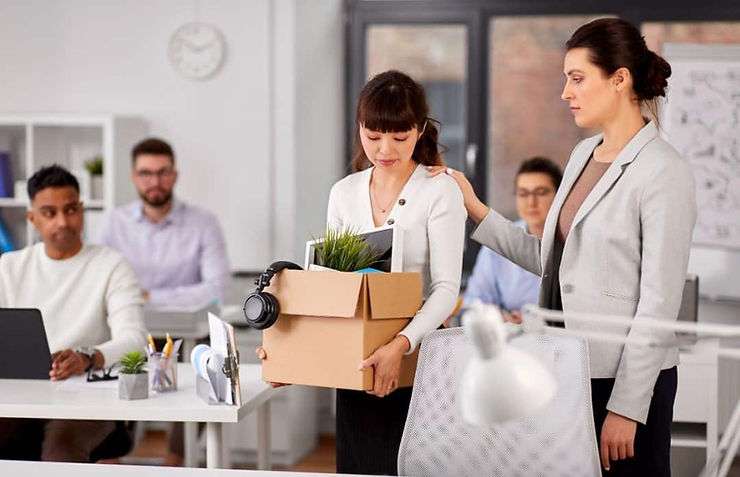 Woman carrying box of things leaving office.